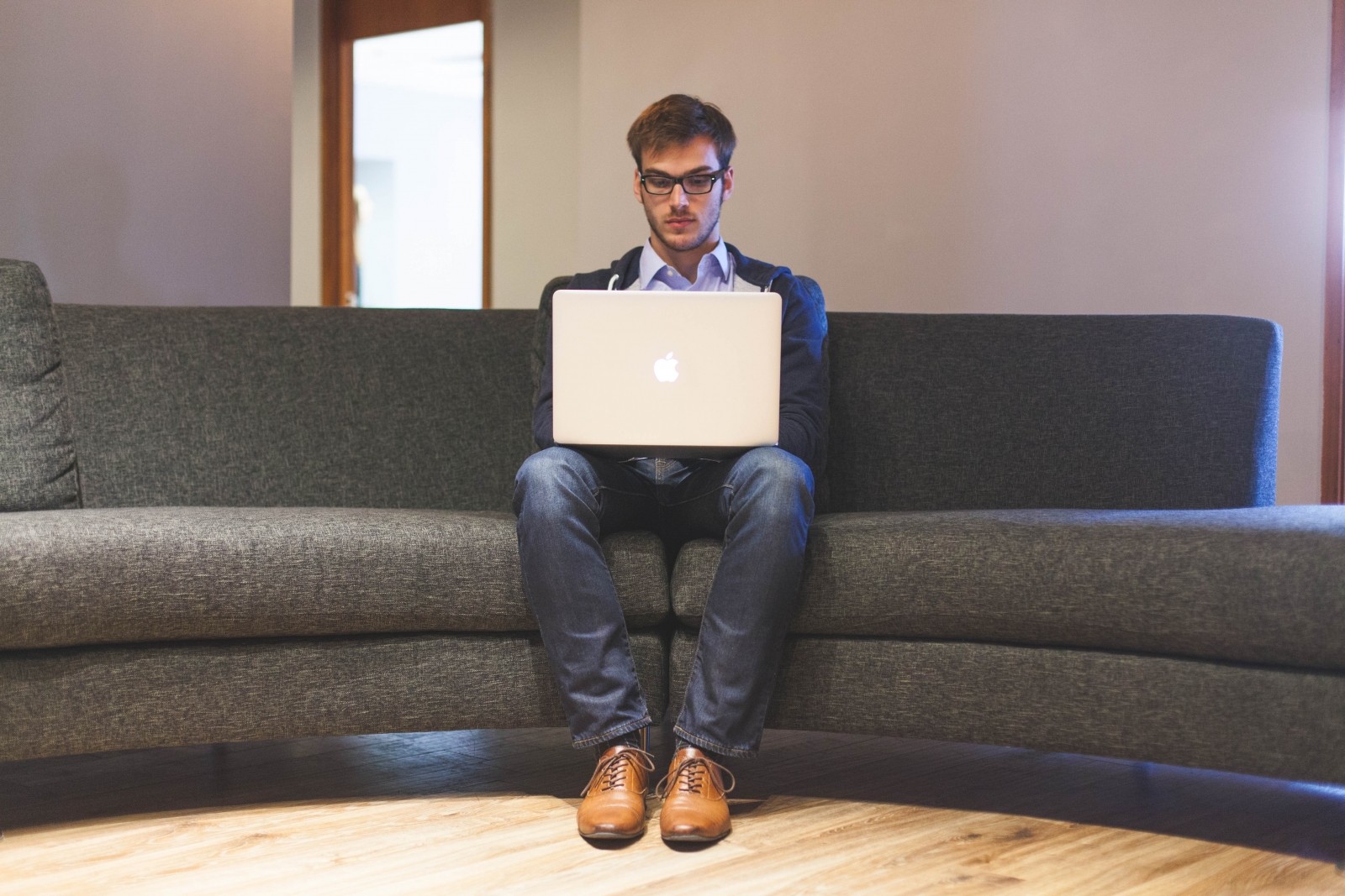 man-sitting-on-sofa-and-using-computer